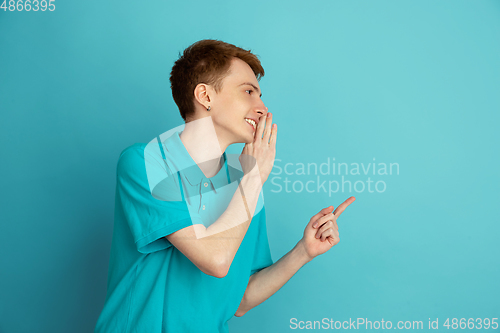 Image of Caucasian young man\'s monochrome portrait on blue studio background, emotinal and beautiful