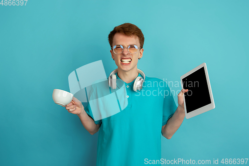 Image of Caucasian young man\'s monochrome portrait on blue studio background, emotinal and beautiful