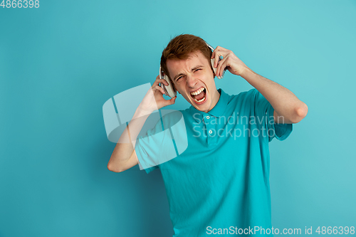 Image of Caucasian young man\'s monochrome portrait on blue studio background, emotinal and beautiful