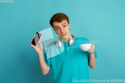 Image of Caucasian young man\'s monochrome portrait on blue studio background, emotinal and beautiful