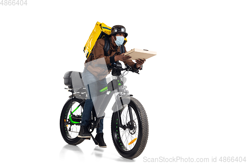 Image of Too much orders. Contacless delivery service during quarantine. Man delivers food and shopping bags during isolation, wearing helmet and face mask.