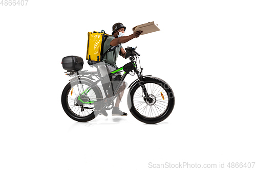 Image of Too much orders. Contacless delivery service during quarantine. Man delivers food and shopping bags during isolation, wearing helmet and face mask.