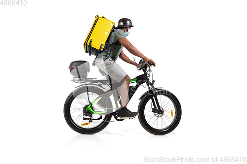 Image of Too much orders. Contacless delivery service during quarantine. Man delivers food and shopping bags during isolation, wearing helmet and face mask.