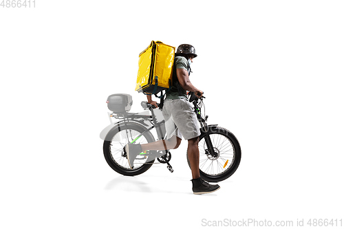 Image of Too much orders. Contacless delivery service during quarantine. Man delivers food and shopping bags during isolation, wearing helmet and face mask.