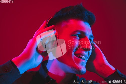 Image of Caucasian man\'s portrait isolated on red studio background in purple-blue neon light, emotional and beautiful, close up
