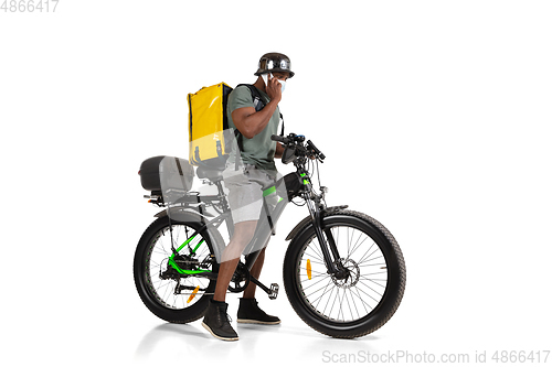 Image of Too much orders. Contacless delivery service during quarantine. Man delivers food and shopping bags during isolation, wearing helmet and face mask.