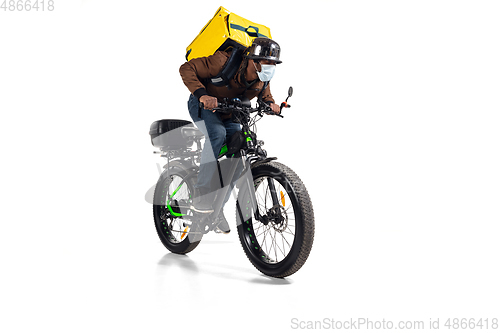 Image of Too much orders. Contacless delivery service during quarantine. Man delivers food and shopping bags during isolation, wearing helmet and face mask.