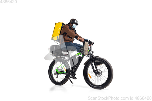 Image of Too much orders. Contacless delivery service during quarantine. Man delivers food and shopping bags during isolation, wearing helmet and face mask.