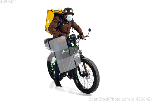 Image of Too much orders. Contacless delivery service during quarantine. Man delivers food and shopping bags during isolation, wearing helmet and face mask.