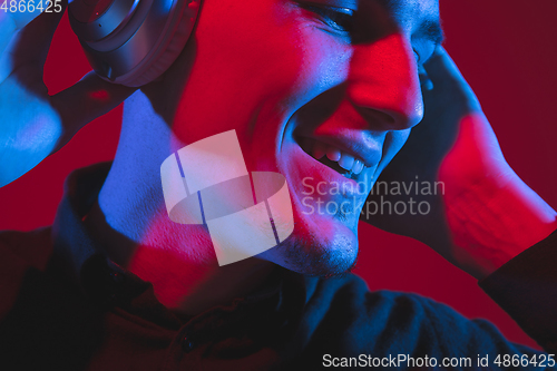 Image of Caucasian man\'s portrait isolated on red studio background in purple-blue neon light, emotional and beautiful, close up