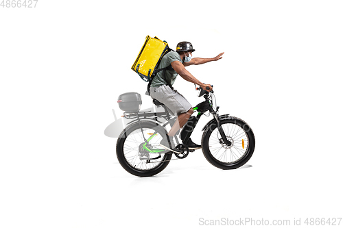 Image of Too much orders. Contacless delivery service during quarantine. Man delivers food and shopping bags during isolation, wearing helmet and face mask.