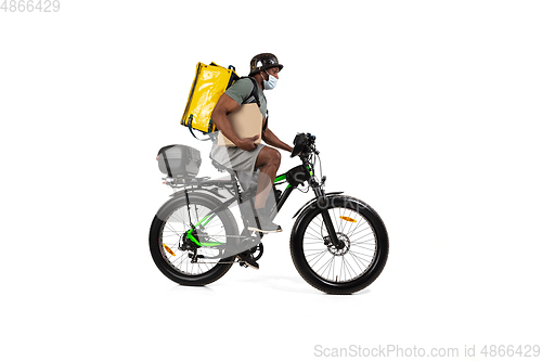 Image of Too much orders. Contacless delivery service during quarantine. Man delivers food and shopping bags during isolation, wearing helmet and face mask.