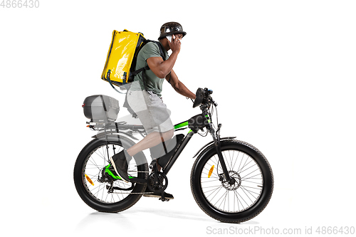 Image of Too much orders. Contacless delivery service during quarantine. Man delivers food and shopping bags during isolation, wearing helmet and face mask.