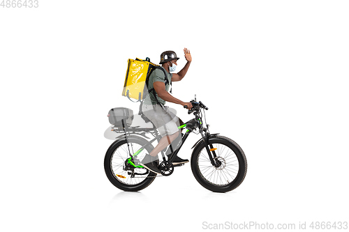 Image of Too much orders. Contacless delivery service during quarantine. Man delivers food and shopping bags during isolation, wearing helmet and face mask.