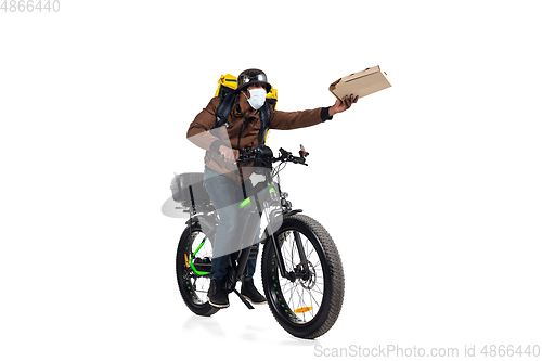 Image of Too much orders. Contacless delivery service during quarantine. Man delivers food and shopping bags during isolation, wearing helmet and face mask.