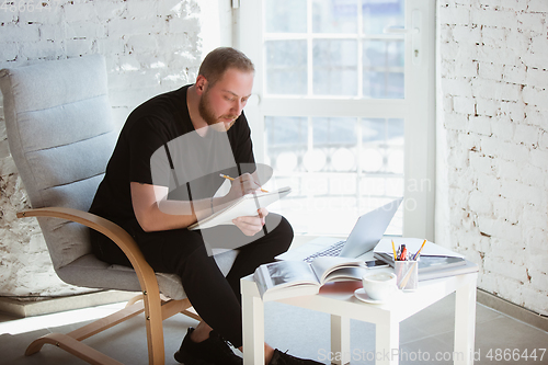 Image of Young man studying at home during online courses for programmer, bug-tester, consulter