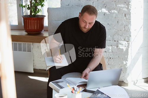 Image of Young man studying at home during online courses for teacher, medical service manager