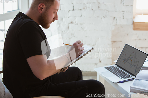 Image of Young man studying at home during online courses for programmer, bug-tester, consulter