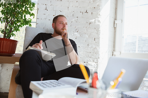 Image of Young man studying at home during online courses for teacher, medical service manager