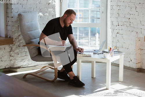 Image of Young man studying at home during online courses for teacher, medical service manager