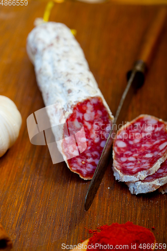 Image of traditional Italian salame cured sausage sliced on a wood board