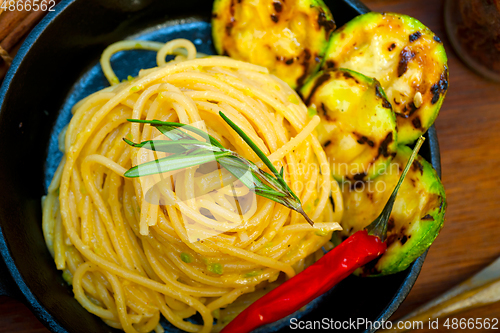 Image of italian spaghetti pasta with zucchini sauce on iron skillet