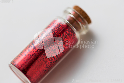 Image of red glitters in bottle over white background
