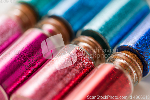 Image of set of different glitters in small glass bottles