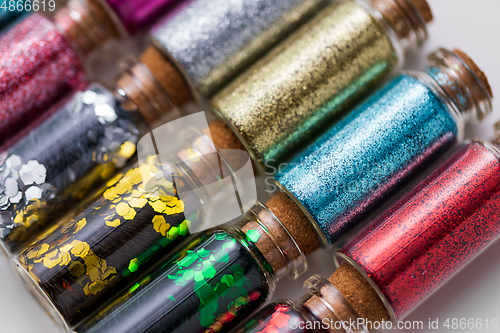 Image of set of different glitters in small glass bottles