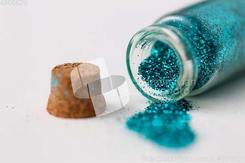 Image of blue glitters poured from small glass bottle