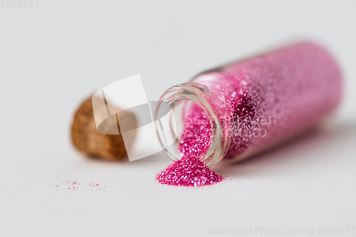Image of pink glitters poured from small glass bottle