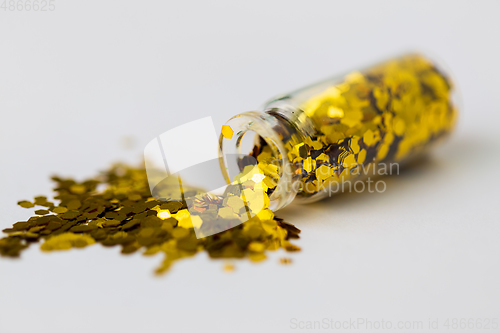 Image of golden glitters poured from small glass bottle