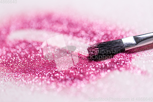 Image of make up brush making stroke on pink glitters