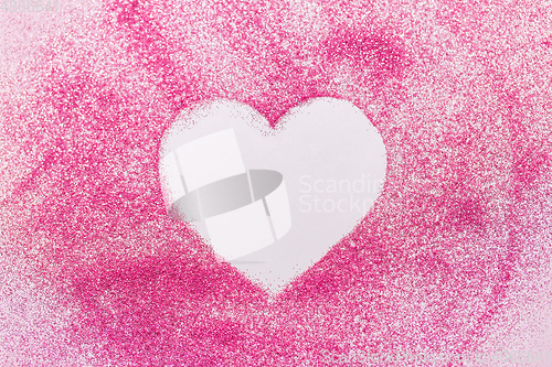 Image of heart shape on pink glitters on white background