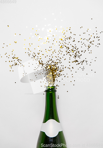 Image of champagne bottle and golden glitters on white