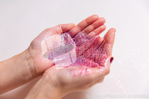 Image of hands holding glitters on white background