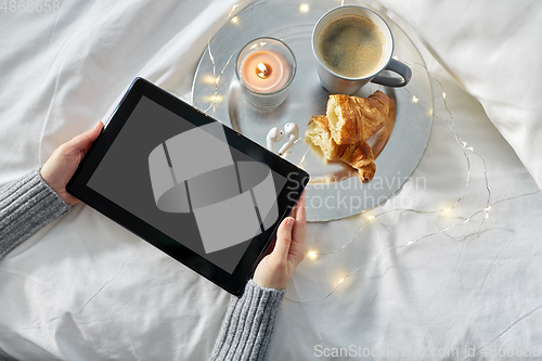 Image of hands with tablet pc, croissant and coffee in bed