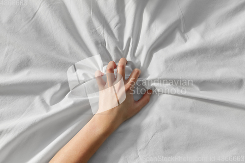 Image of hand of woman squeezing white bed sheet