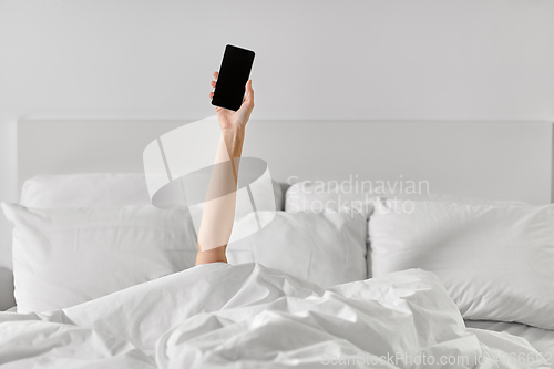 Image of hand of woman lying in bed with smartphone