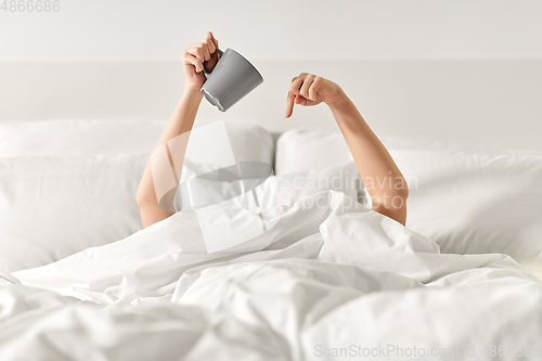 Image of woman with cup of coffee lying in bed