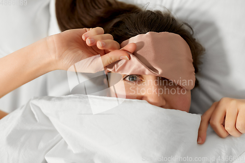 Image of woman with eye sleeping mask in bed under blanket