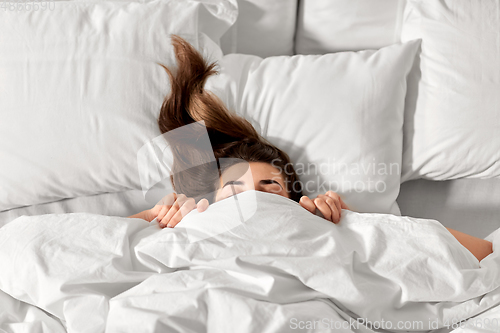 Image of woman lying in bed under white blanket or duvet