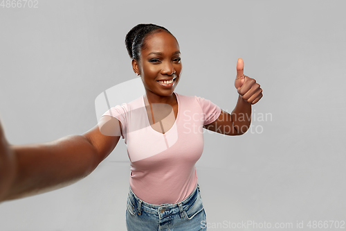 Image of african woman taking selfie and showing thumbs up