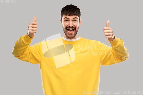 Image of smiling young man showing thumbs up