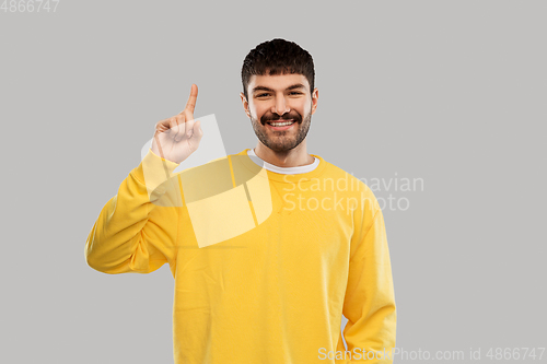 Image of young man showing one finger in yellow sweatshirt