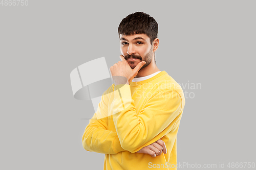 Image of thinking young man in yellow sweatshirt