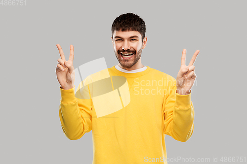 Image of young man showing peace over grey background