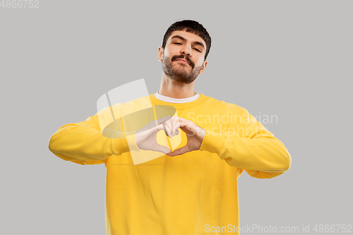 Image of young man in yellow sweatshirt l making hand heart