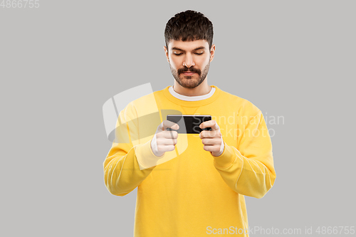 Image of young man playing game on smartphone