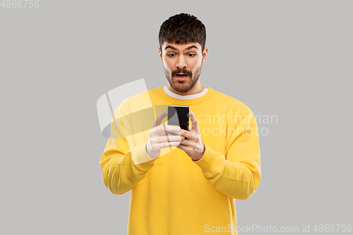 Image of surprised young man with smartphone